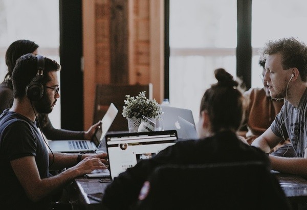 A sales team sitting at a table with laptops working independently on sales effectiveness.